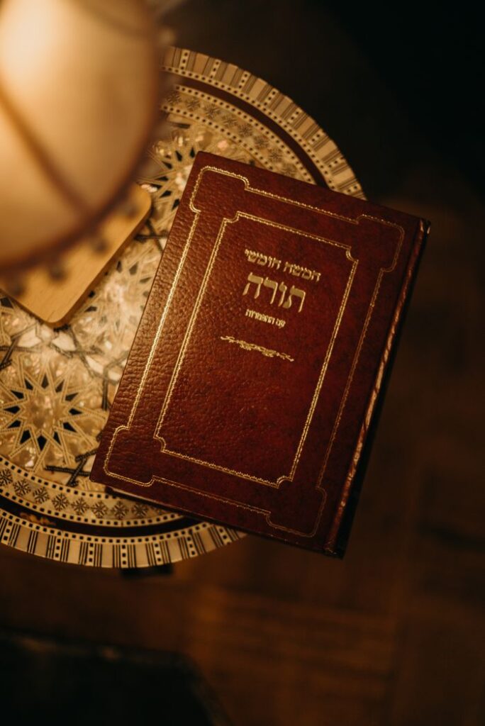 A beautifully decorated Jewish book placed on an intricate table, warmly lit.